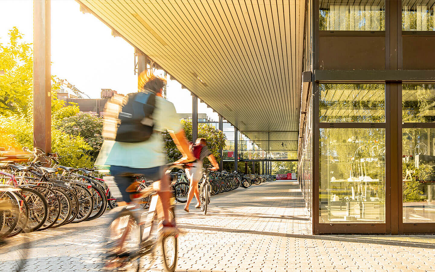 Zwei Personen auf dem Fahrrad vor einer Hochschule | Abifor